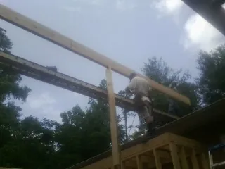 Carpenter setting a ridge beam over a new addition frame — Ice Dam Removal by Roofing Brothers in Mamaroneck