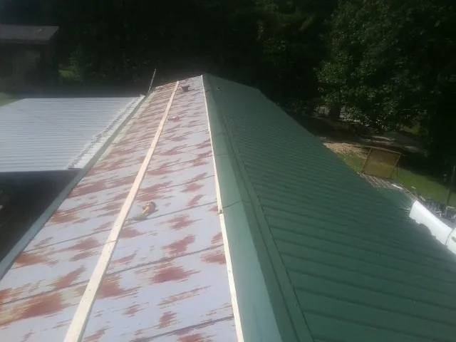 Old rusted panels beside newly installed green metal roofing — Wind Damage Roof Repair by Roofing Brothers in Mamaroneck