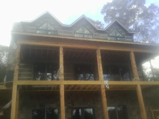 Dormers and porch framing on a large log home under construction — Roof Coating work by our crew in Mamaroneck