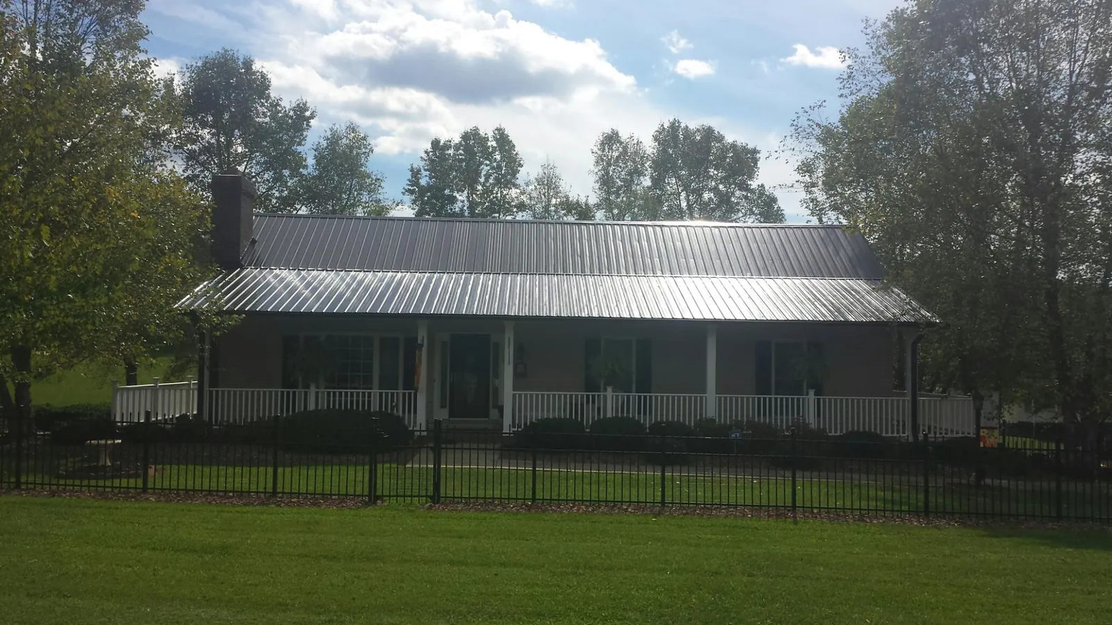 Gray metal roof on a brick ranch with a full width front porch — Gutter Guard Installation work by our crew in Mamaroneck