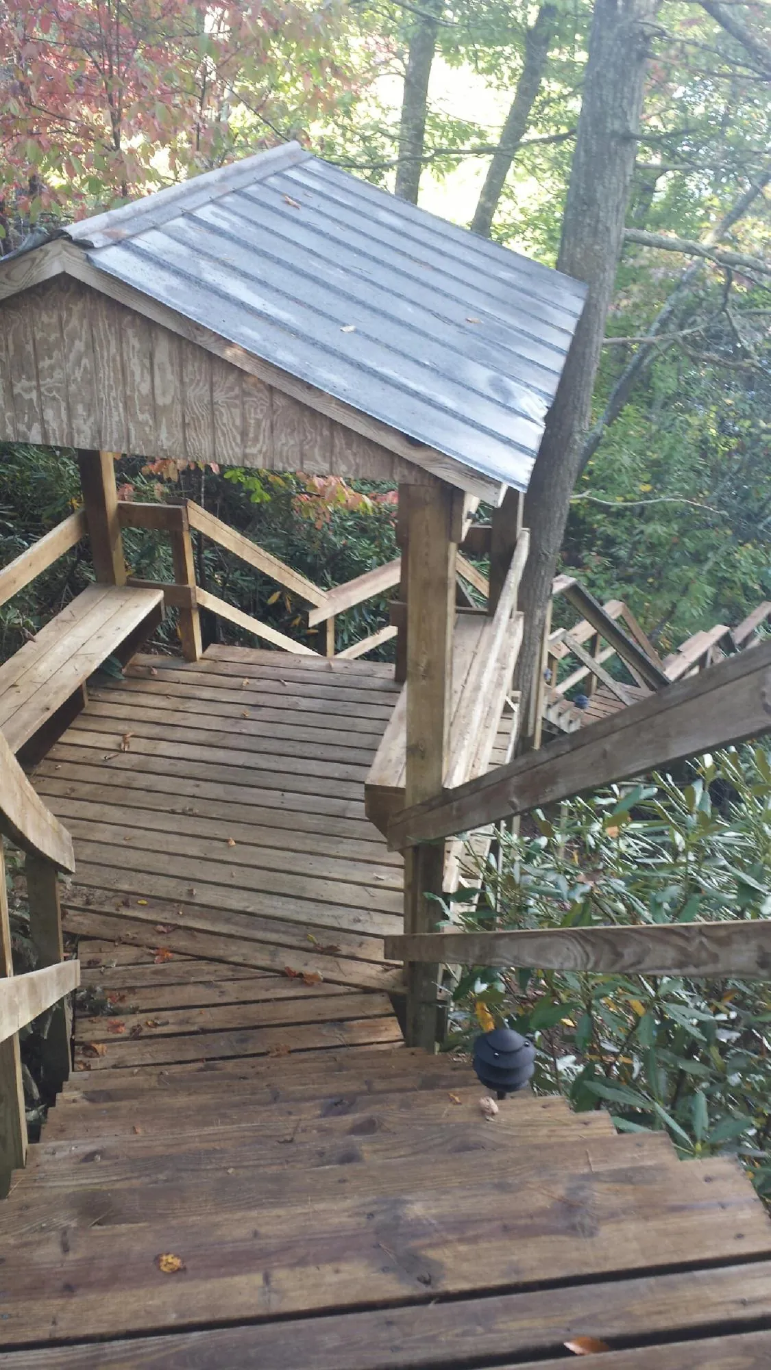 Metal roofed shelter over wooden steps on a wooded walkway — Skylight Repair & Installation work by our crew in Mamaroneck