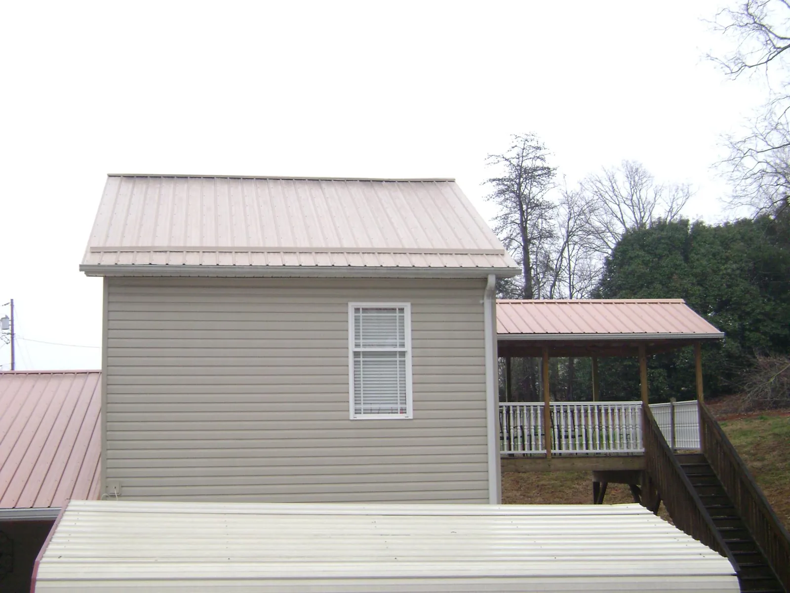Tan metal roofs on a two story addition and attached porch, from a Roof Replacement job in Mamaroneck