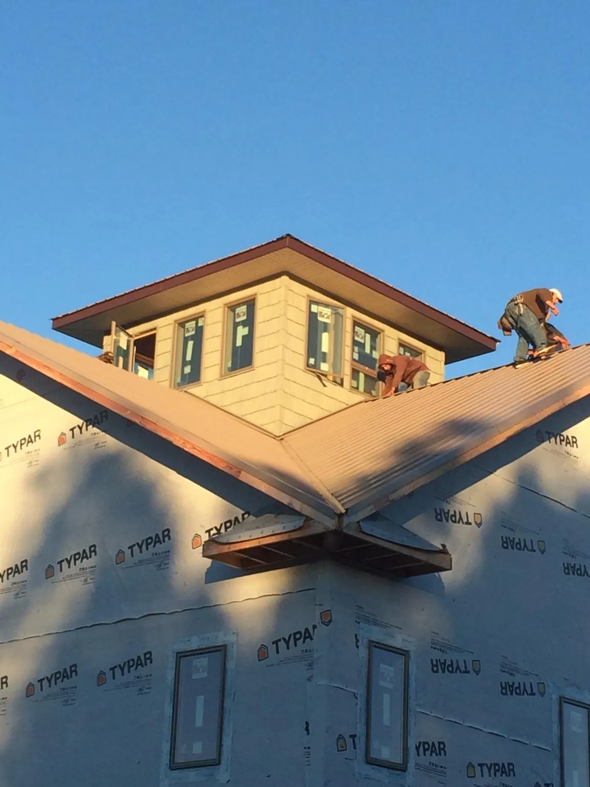 Roofers working around a rooftop cupola on a new metal roof at sunset — Roof Waterproofing in Mamaroneck by Roofing Brothers